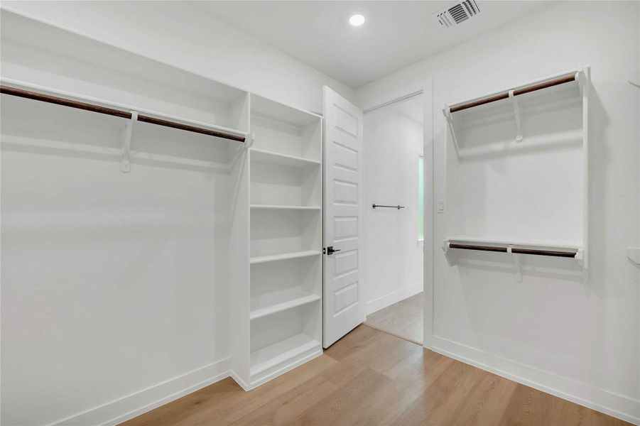 Walk in closet with visible vents and wood finished floors Walk in closet with visible vents and wood finished floors