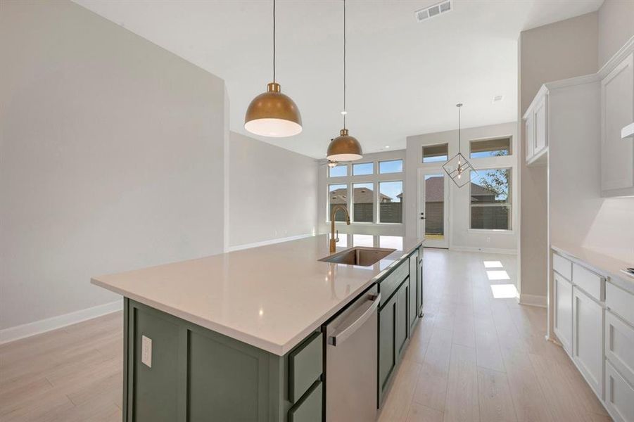 Kitchen island with a light-toned countertop, integrated stainless steel sink, and dishwasher