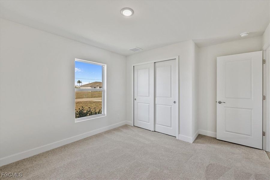 Unfurnished bedroom featuring light carpet and a closet