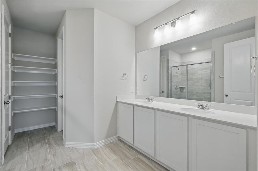 Bathroom featuring a shower stall and double vanity