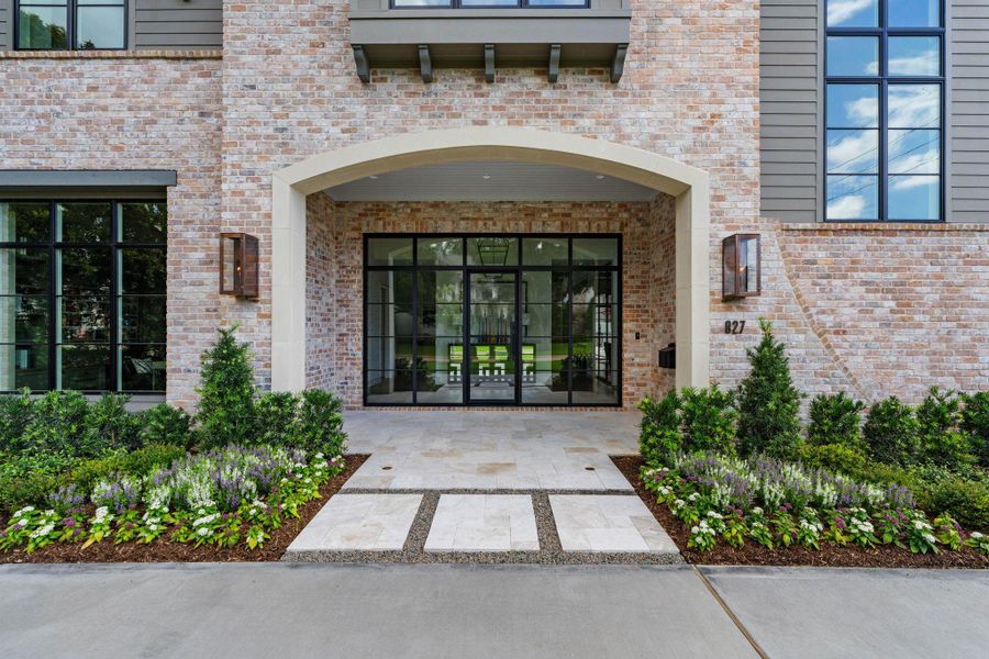 [Front Entrance]An arched portico with brick walls and stone hardscape encloses the glass front doors. Note beadboard ceiling.