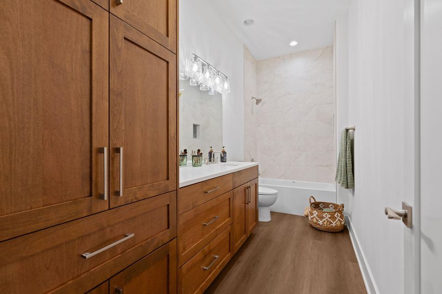 Bathroom with wood finished floors, toilet, vanity, shower / washtub combination, and recessed lighting Bathroom with wood finished floors, toilet, vanity, shower / washtub combination, and recessed lighting