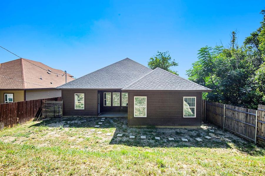 Back of house featuring a shingled roof and a fenced backyard
