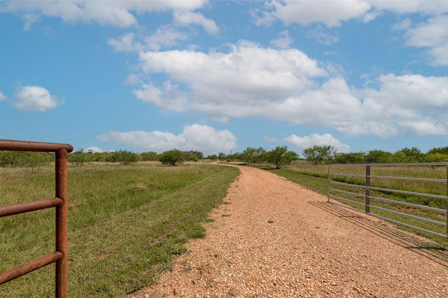 View of dirt / gravel driveway with a view of rural / pastoral area, a gated entry, and a gate