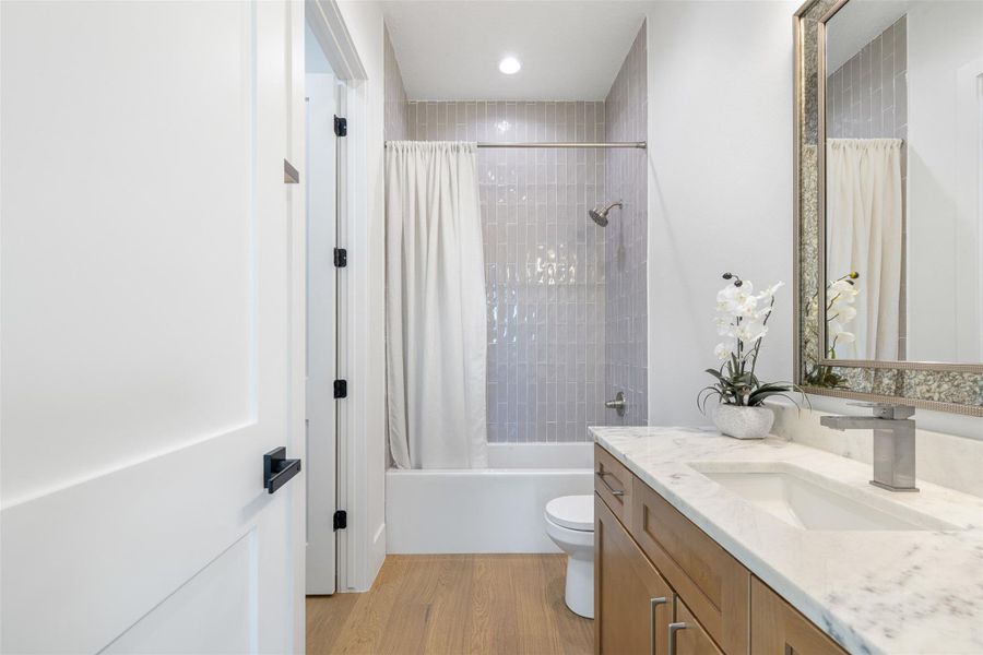Bathroom featuring shower / bath combo, light wood finished floors, vanity, and recessed lighting