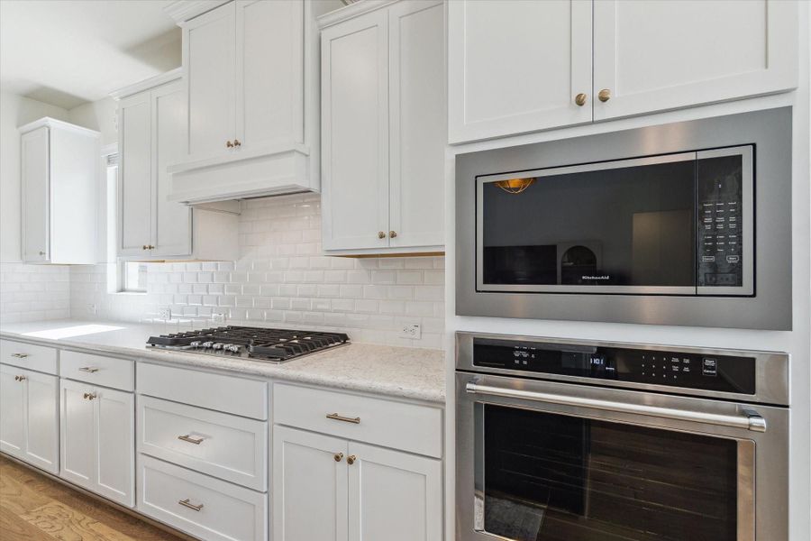 Kitchen detail highlighting modern kitchenaid stainless steel appliances, generous storage, and a stylish backsplash.