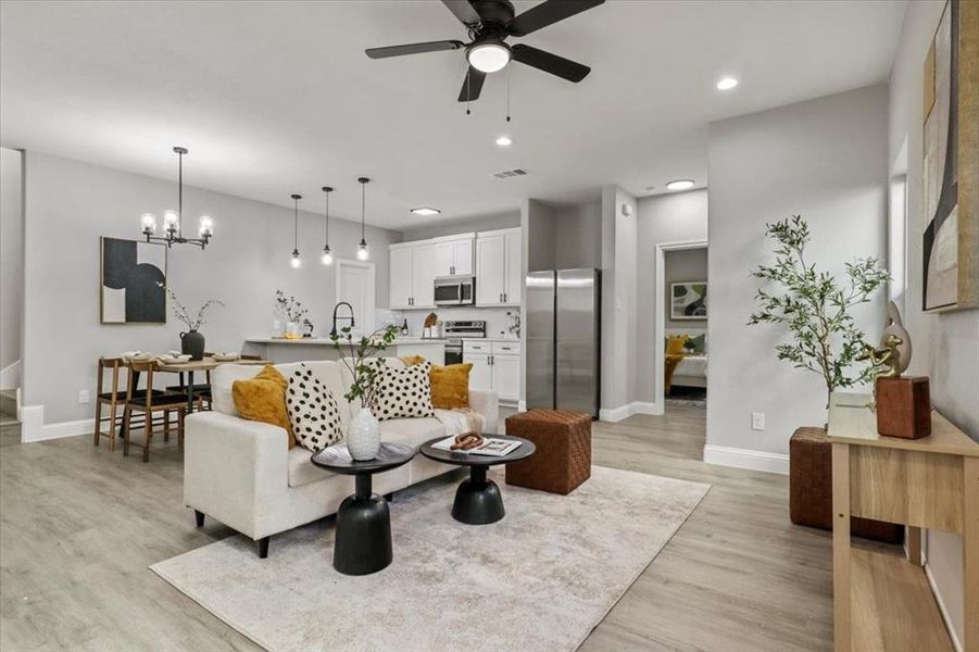 Living room with ceiling fan with notable chandelier, light hardwood / wood-style floors, and sink