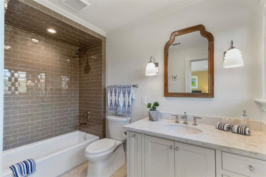 Full bathroom with ornamental molding, tiled shower / bath combo, vanity, and toilet