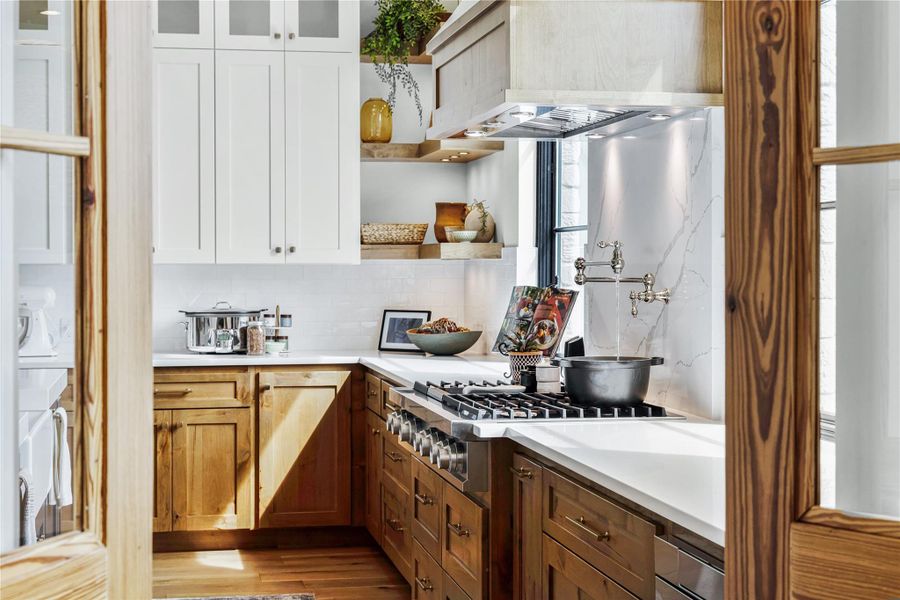 Kitchen with white cabinetry, tasteful backsplash, stainless steel gas stovetop, light hardwood / wood-style floors, and wall chimney range hood