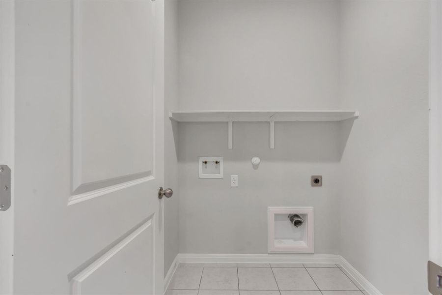 A well-appointed laundry room awaits your personal touch, complete with shelving and hookups.