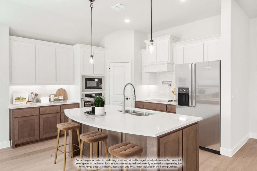 Kitchen with white upper cabinets, brown lower cabinets, center island with seating, and stainless steel appliances