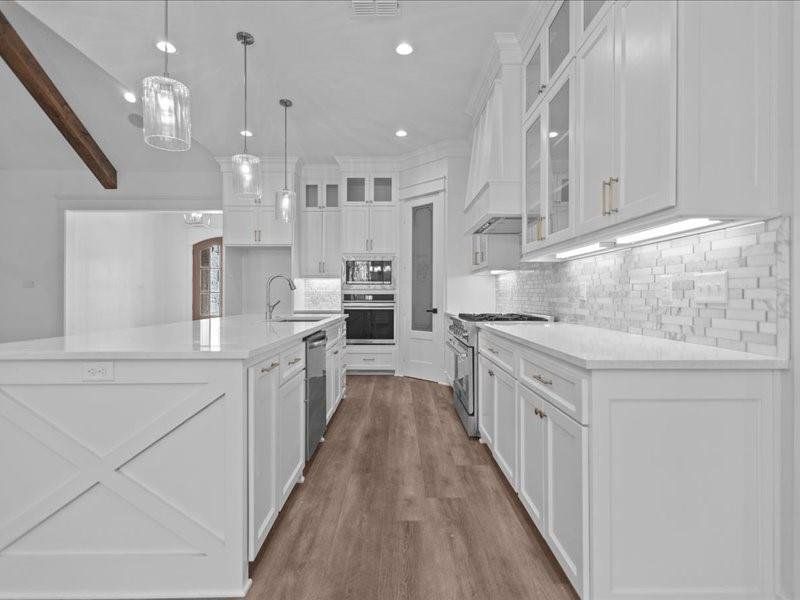 Kitchen with glass insert cabinets, backsplash, appliances with stainless steel finishes, white cabinets, and recessed lighting