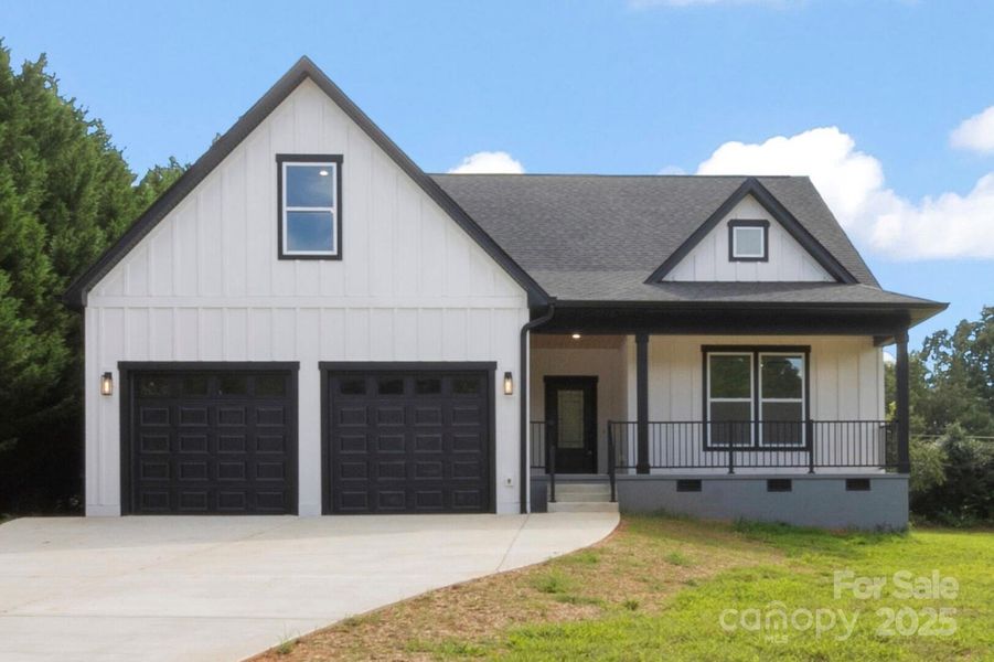 Front view of this modern farmhouse custom home.Vertical  Hardie board and batten siding. Large driveway with extra parking. Side entrance door to garage with sidewalk