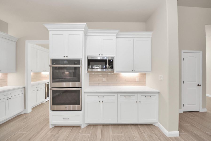 Ample counter space and a neutral color palette create a bright, inviting atmosphere in this kitchen with double ovens.