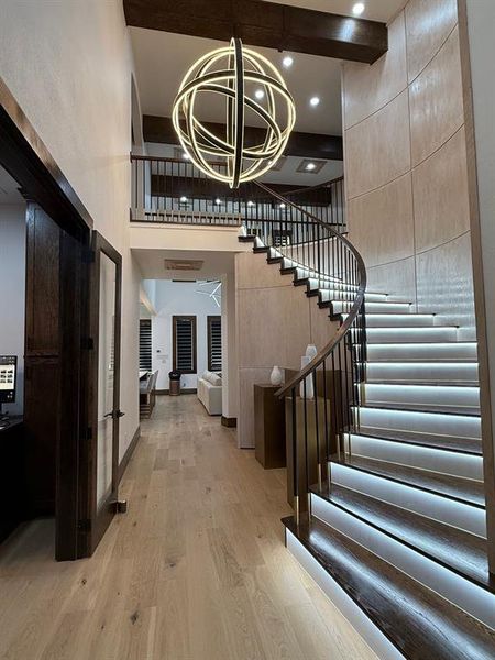 Entrance foyer with light wood-style flooring, stairway, a chandelier, and a towering ceiling