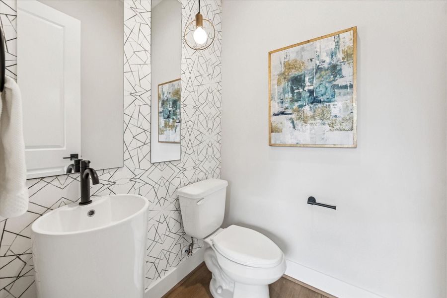 Powder bath conveniently located on the 2nd floor with a fun wallpapered accent wall, light fixture and pedestal sink.