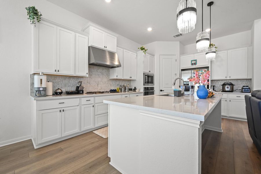 Elegant white cabinetry pairs seamlessly with a substantial central island and durable wood-look flooring.
