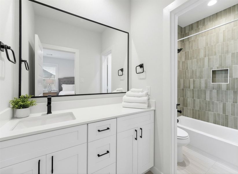 Third floor bathroom featuring a quartz-topped vanity, matte black fixtures, and a tub-shower combo with warm vertical tile for a modern, spa-inspired finish. *Virtually staged*