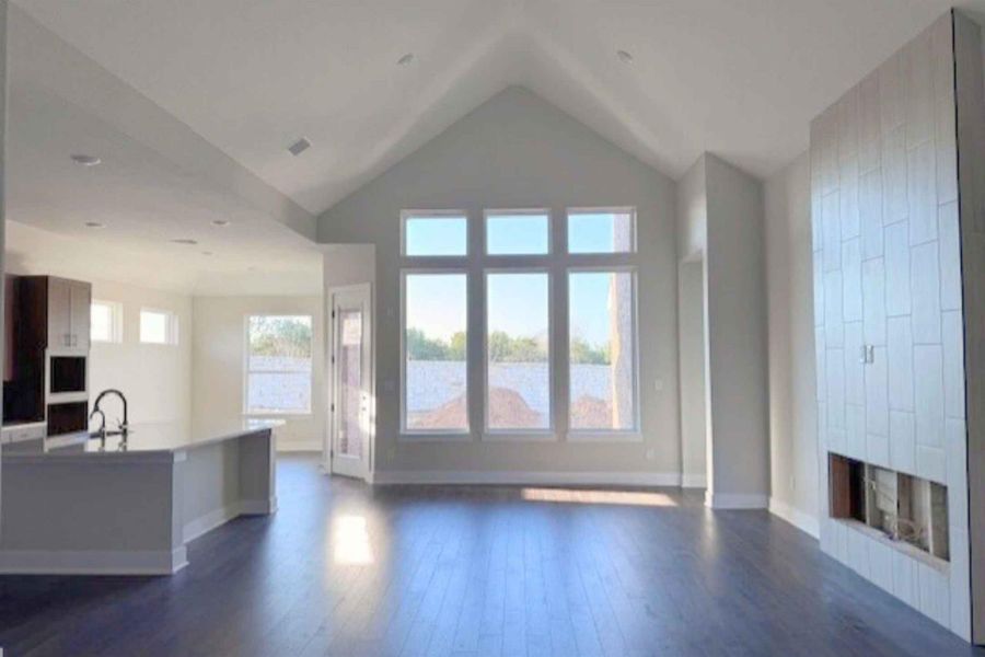 Unfurnished living room with dark wood-type flooring, a fireplace, and a high ceiling