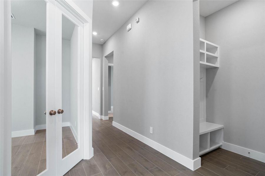This dedicated area features a custom built-in bench with hooks, perfect for organizing coats, bags, and shoes right off the main hallway, keeping the rest of the home tidy.