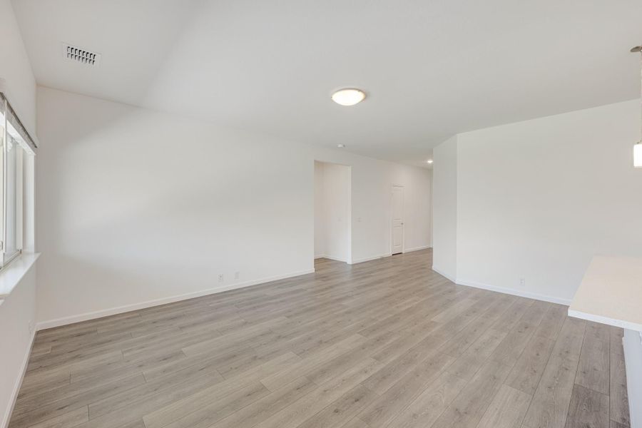 Empty living room with light gray laminate floors, white walls, and vaulted ceiling Empty living room with light gray laminate floors, white walls, and vaulted ceiling