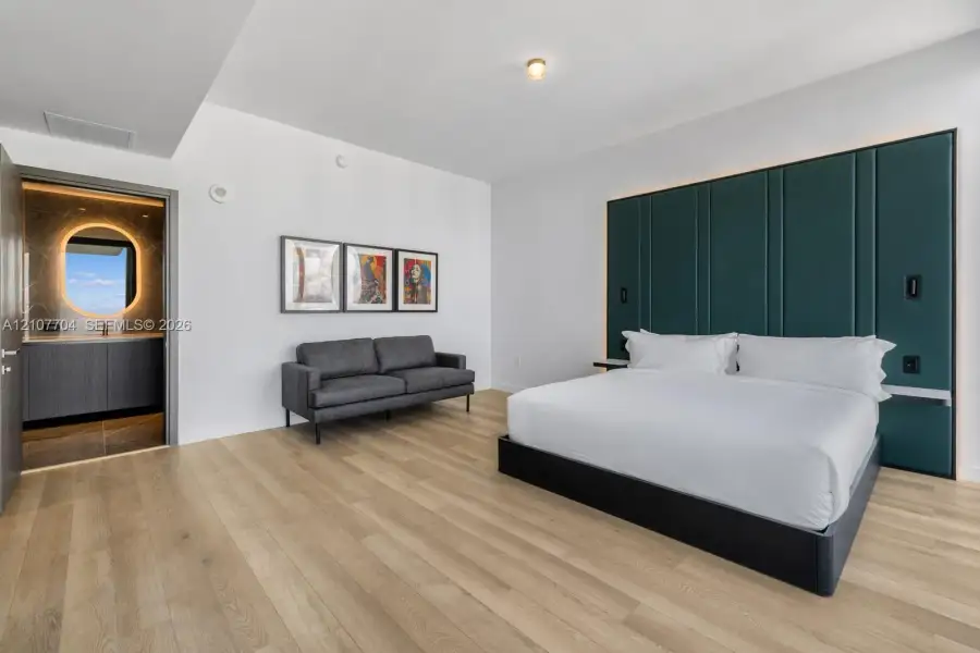 Room featuring wide-plank wood-finish flooring, floor-to-ceiling dark green paneled accent wall, and recessed ceiling lighting