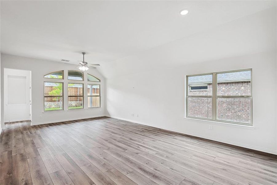 Spare room with vaulted ceiling, light wood-type flooring, and ceiling fan