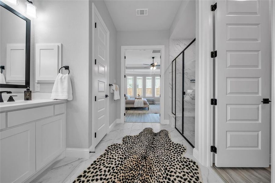 Full bathroom with a marble finish shower, vanity, a ceiling fan, light marble finish flooring, and connected bathroom Full bathroom with a marble finish shower, vanity, a ceiling fan, light marble finish flooring, and connected bathroom
