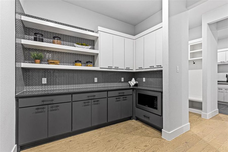 Kitchen with gray cabinetry, open shelves, light wood finished floors, and backsplash