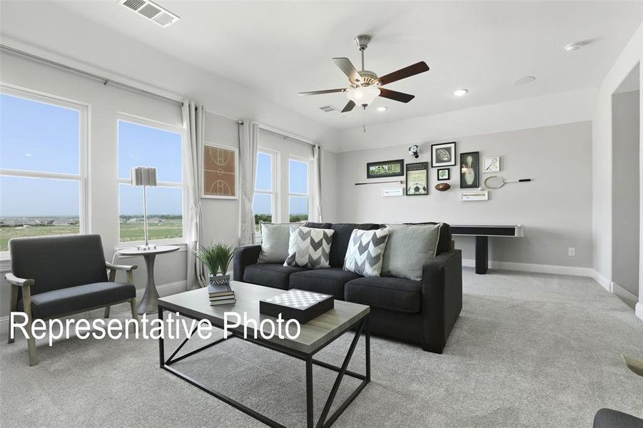 Carpeted living room with ceiling fan and a wealth of natural light