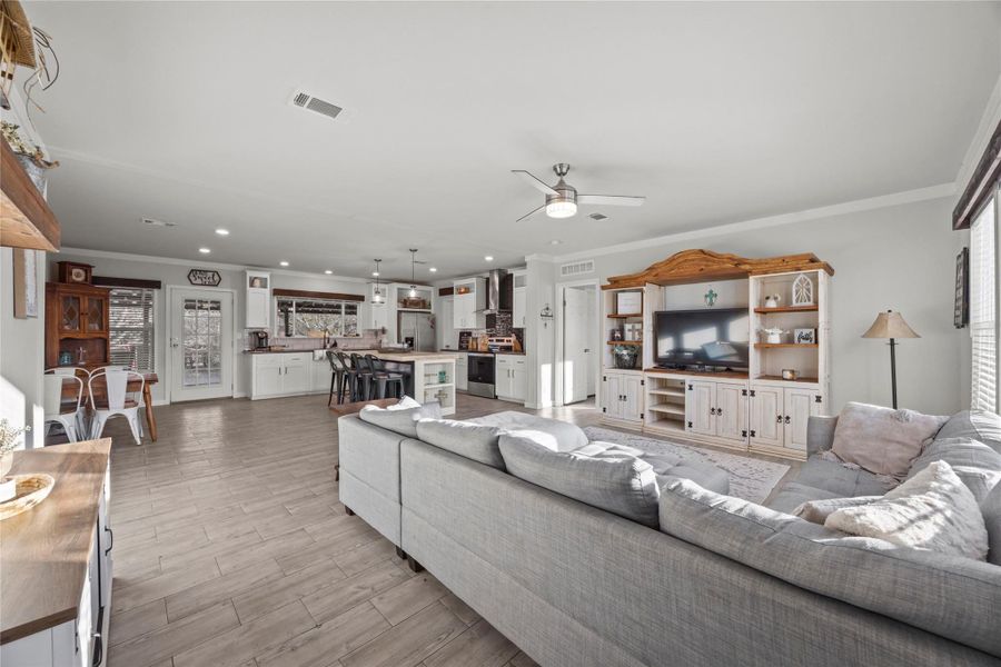Living area featuring ornamental molding, healthy amount of natural light, ceiling fan, light wood finished floors, and recessed lighting