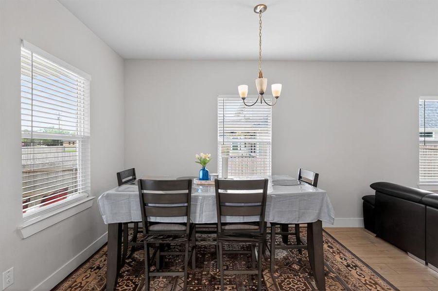 Dining area featuring a contemporary chandelier, a window with blinds, and light-colored walls