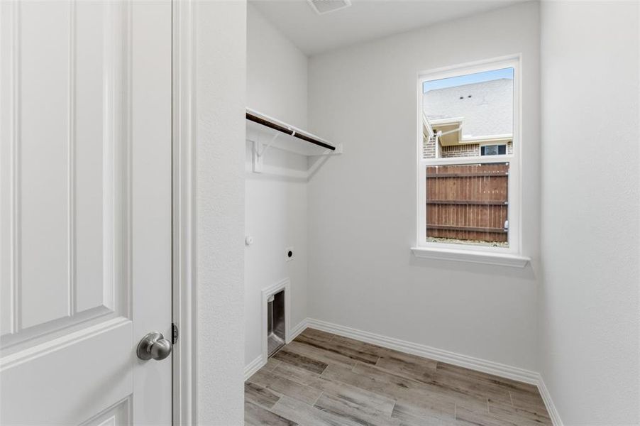 Laundry room with electric dryer hookup and light wood-type flooring