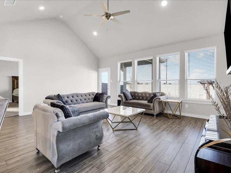 Living room with hardwood / wood-style floors, ceiling fan, and high vaulted ceiling