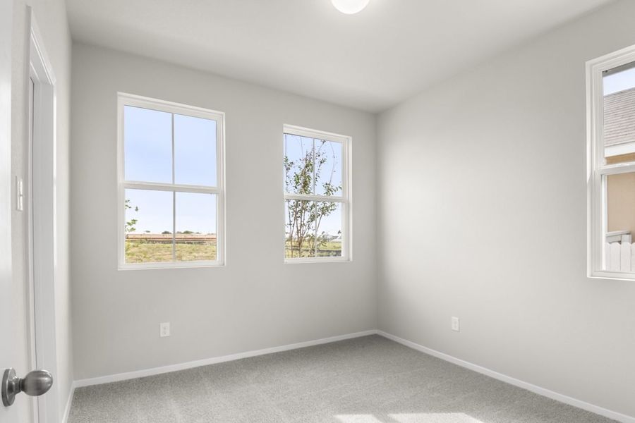 Image of bedroom with light grey walls and carpet with two windows
