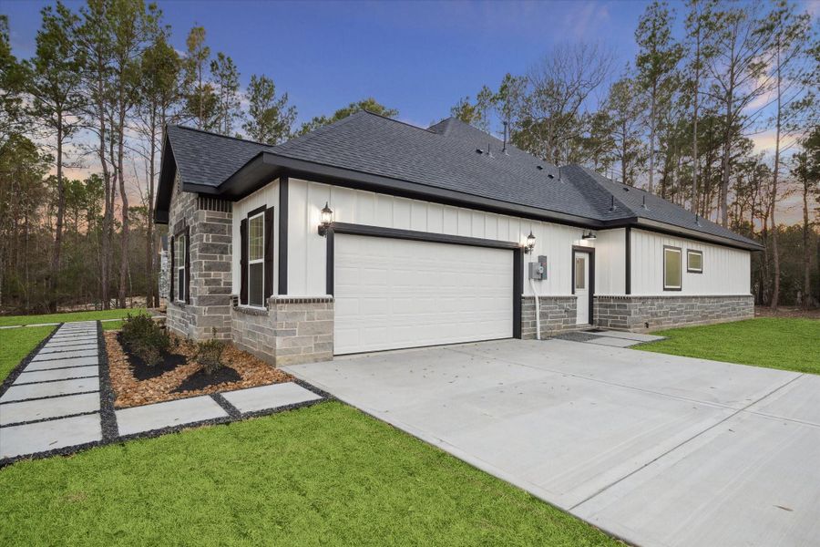 View of the home from Bronco Lane toward the side of the home.   Three coach lights.  Entry door opens to the utility room.   Two windows on the far right are the primary bathroom.