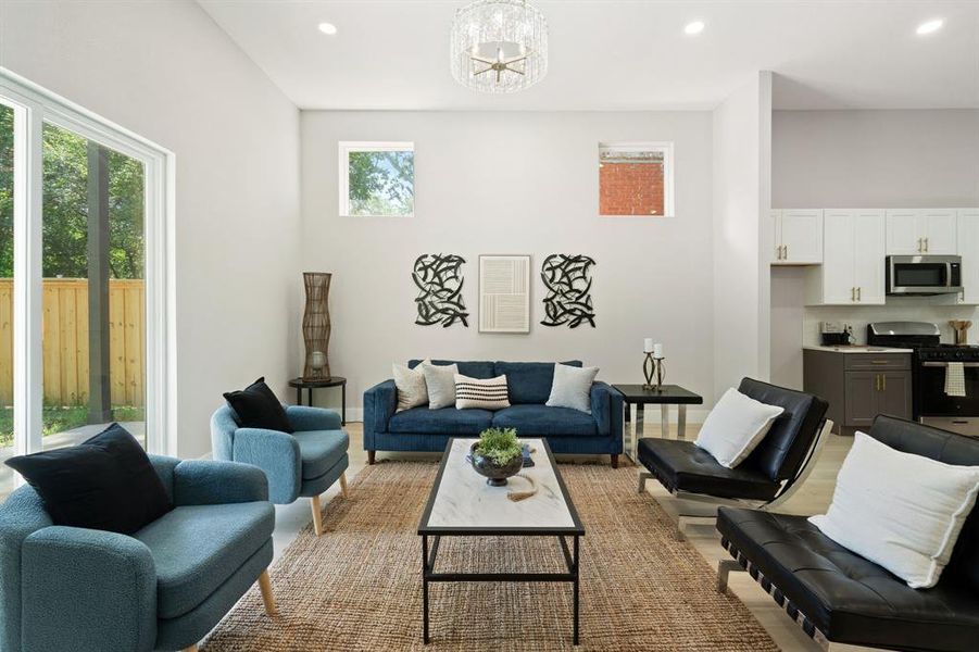 Spacious living area featuring high ceilings, recessed lighting, and a modern chandelier Spacious living area featuring high ceilings, recessed lighting, and a modern chandelier