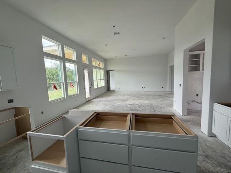 A spacious, luminous open-plan interior awaiting final touches, featuring abundant windows.