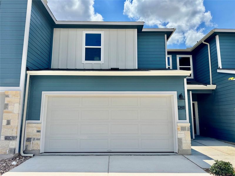 View of front of home with stone siding, board and batten siding, an attached garage, and concrete driveway View of front of home with stone siding, board and batten siding, an attached garage, and concrete driveway
