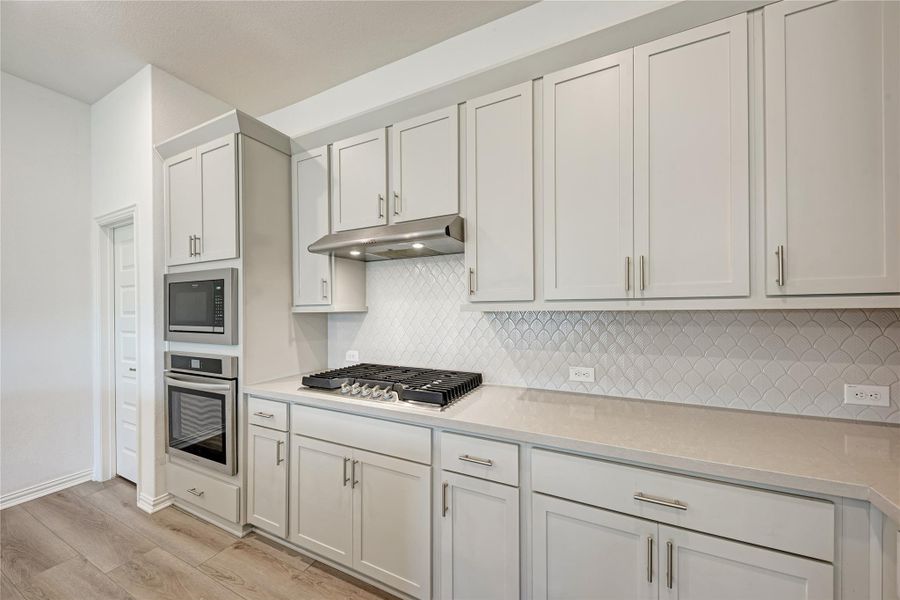 A well-appointed kitchen features a gas range, built-in microwave and oven, and ample cabinetry with sleek hardware.