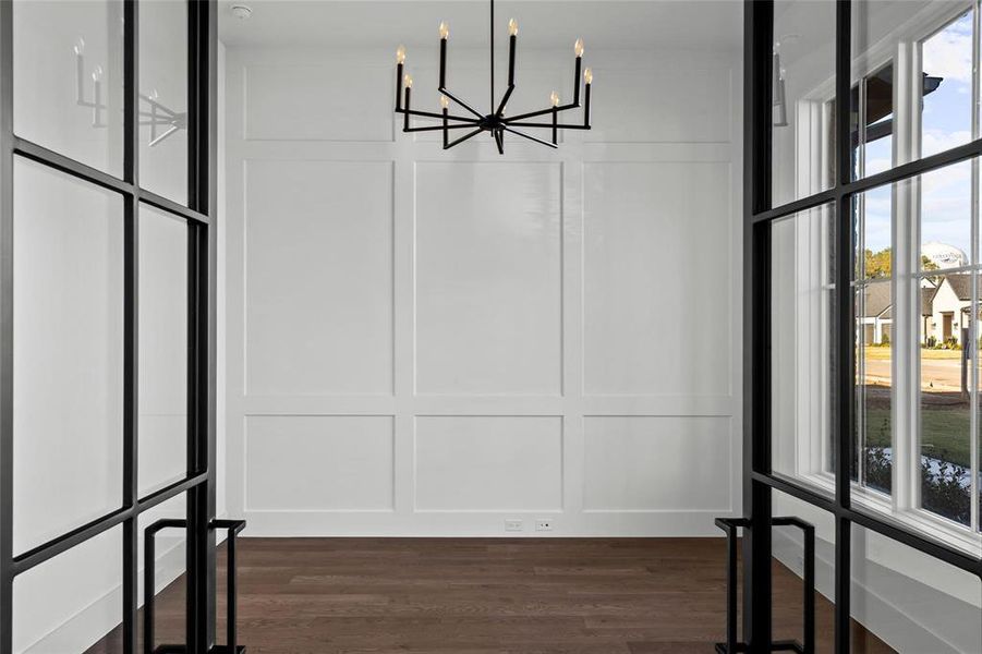 Unfurnished dining area with plenty of natural light, a decorative wall, dark wood-type flooring, and a chandelier Unfurnished dining area with plenty of natural light, a decorative wall, dark wood-type flooring, and a chandelier