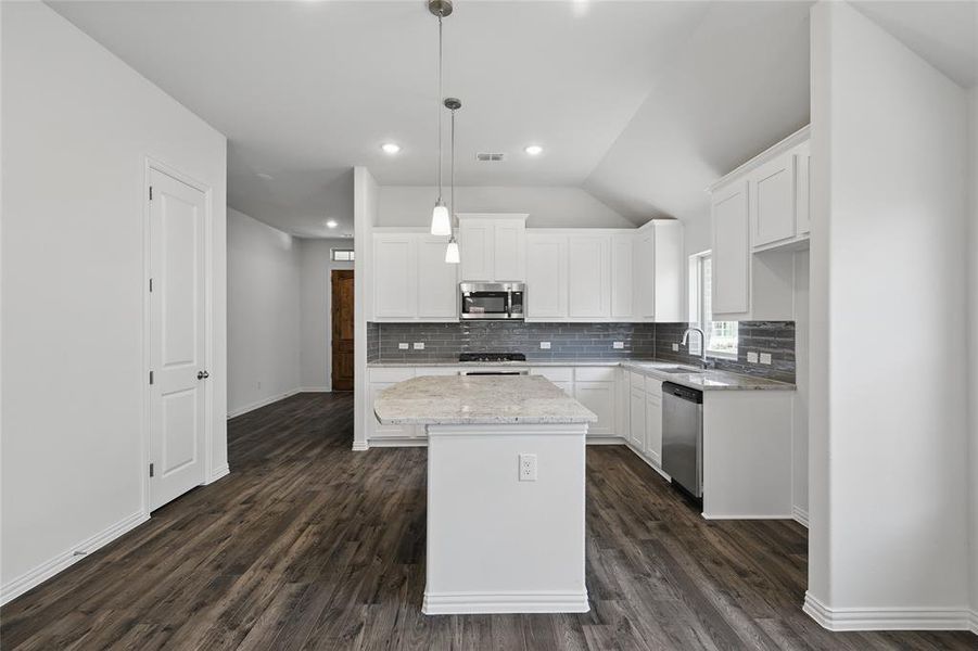 Kitchen with tasteful backsplash, appliances with stainless steel finishes, dark wood-type flooring, and a sink