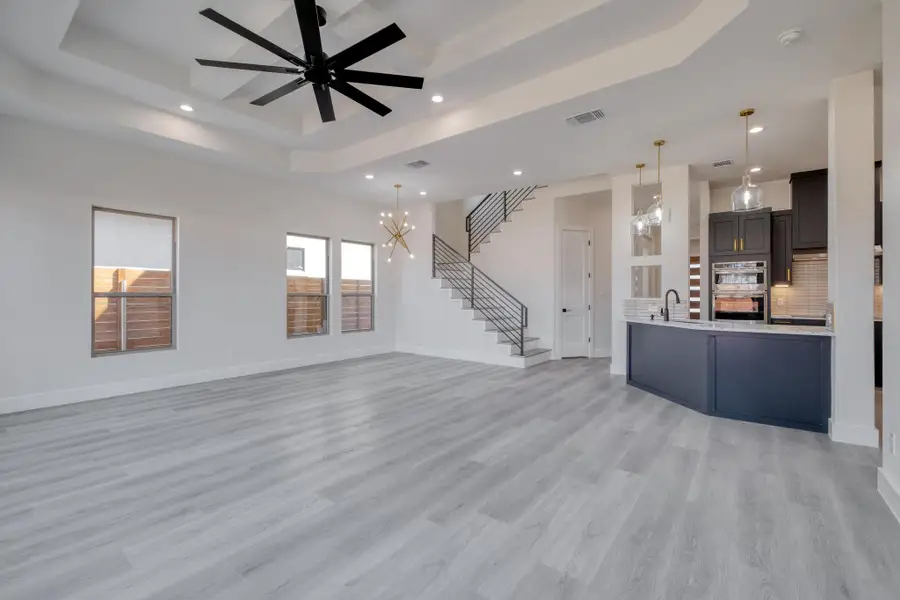 Unfurnished living room featuring visible vents, a sink, baseboards, stairway, and a raised ceiling