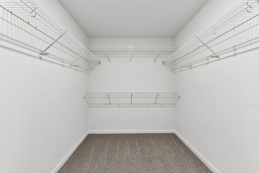 Walk-in closet featuring white wire shelving, white textured walls, and grey carpet flooring