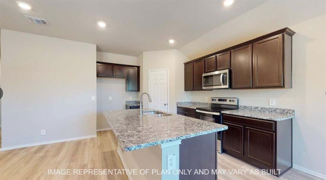 Kitchen with dark wood finish cabinets, stainless steel appliances, light wood finished floors, light stone countertops, and recessed lighting