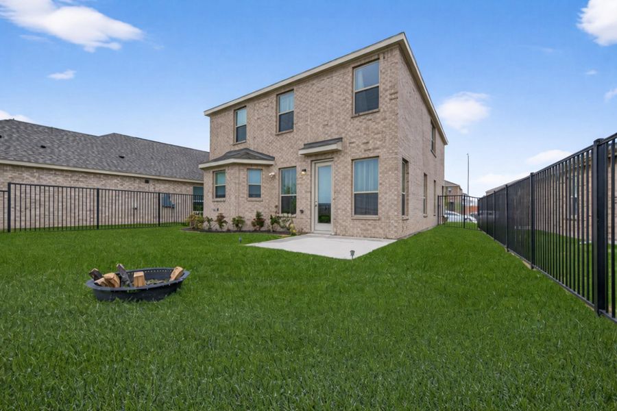 Extended concrete patio and fenced backyard behind modern white brick, offering open views and privacy.