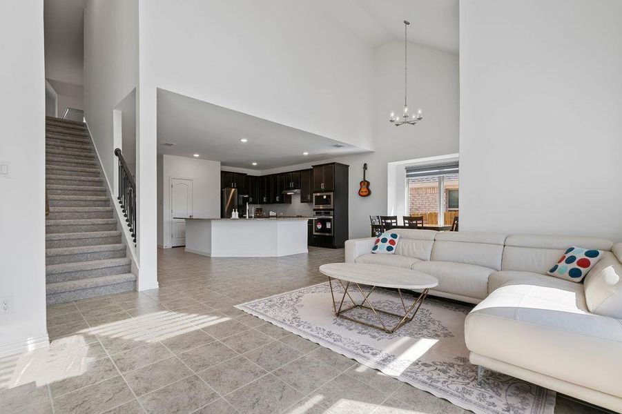 Living area with a chandelier, a high ceiling, and light tile patterned floors Living area with a chandelier, a high ceiling, and light tile patterned floors