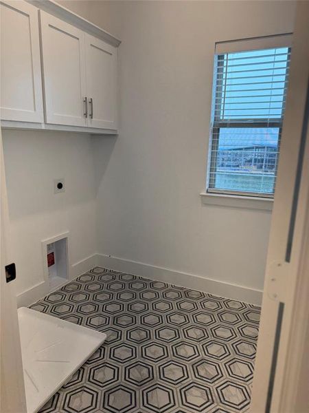 Laundry room featuring tile patterned flooring, cabinet space, hookup for an electric dryer, and baseboards