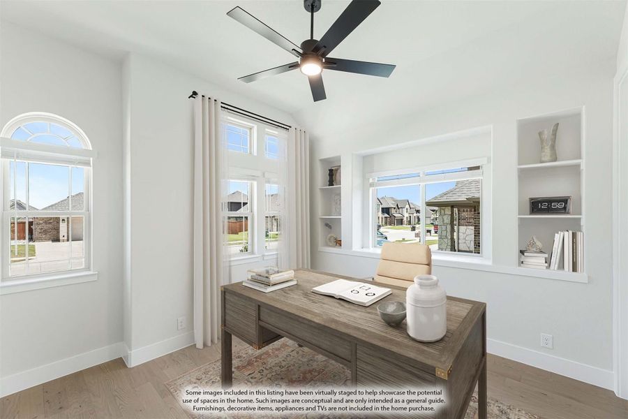 Home office with wood desk, built-in shelves, ceiling fan, and large windows with natural light Home office with wood desk, built-in shelves, ceiling fan, and large windows with natural light