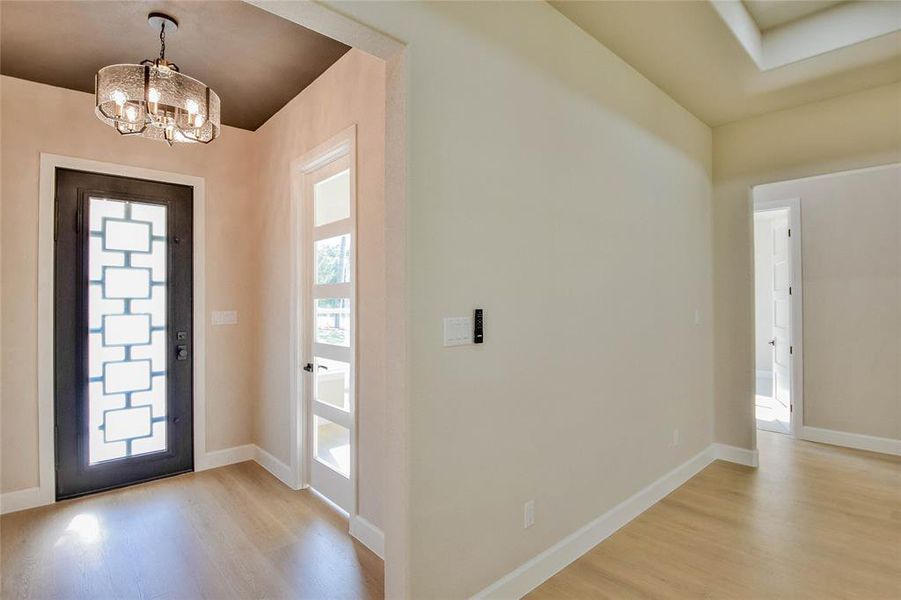 Foyer entrance featuring light wood-style floors and a chandelier Foyer entrance featuring light wood-style floors and a chandelier